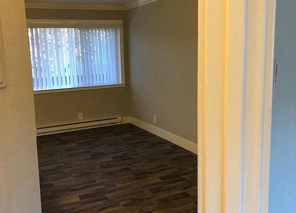 A room with a window and wooden flooring.