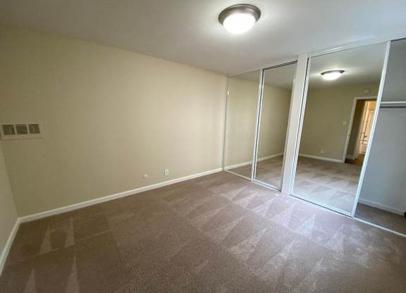 an empty living room with mirrored closet doors