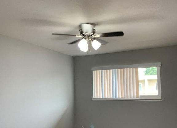 A room with a ceiling fan and carpeted floor.
