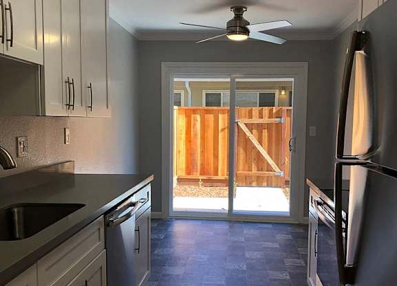A kitchen with a checkered floor and a ceiling fan.