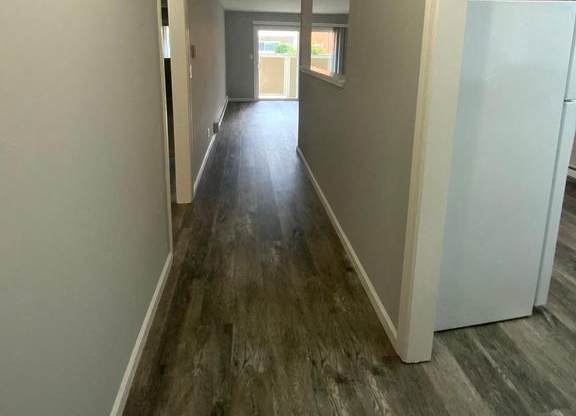 A long hallway with wood floors and white walls.