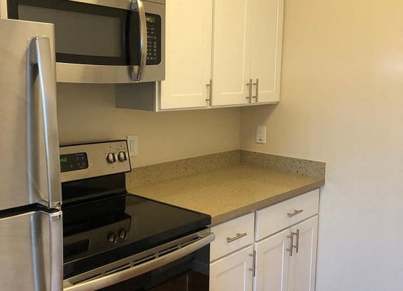 a kitchen with a stove and microwave and white cabinets