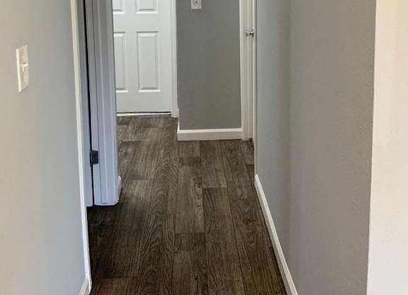 A hallway with a white door and a wooden floor.