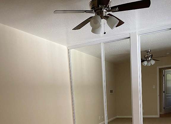 an empty living room with a ceiling fan