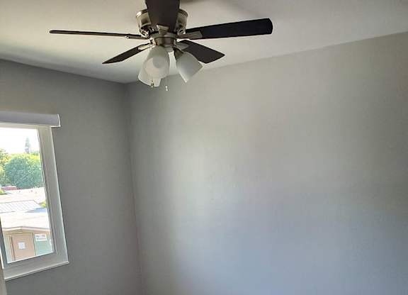A room with a ceiling fan and carpeted floor.