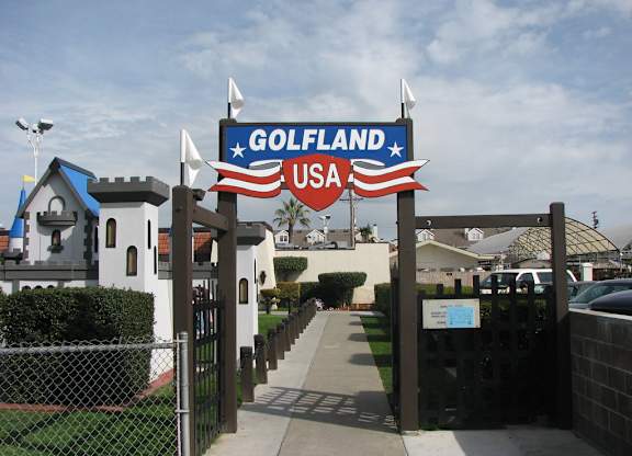 A sign that says Golfland USA is in front of a fence.