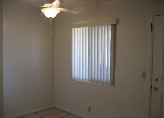 A room with a ceiling fan and a window with blinds.