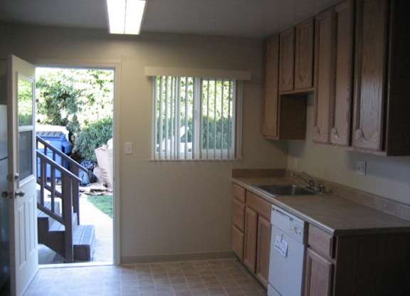 A kitchen with a dishwasher and wooden cabinets.