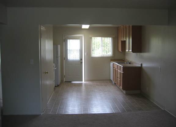 A kitchen with a sink, cabinets, and a window.