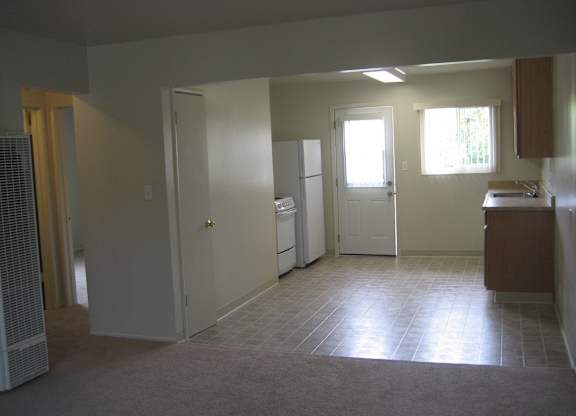 A kitchen area with a refrigerator, sink, and cabinets.