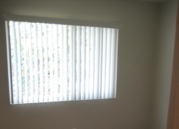 A room with a carpet floor and a window with blinds.