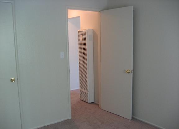 A white door is open to a room with a white wall and a white closet.