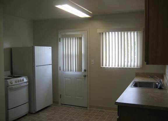 A kitchen with a white refrigerator, a white stove, and a white door.