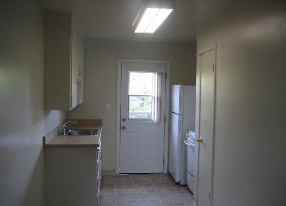 A kitchen with a sink, refrigerator, and a door leading to a patio.
