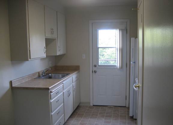 A kitchen with white cabinets and a white door.