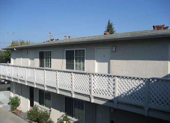 A building with a balcony and a tree in the background.
