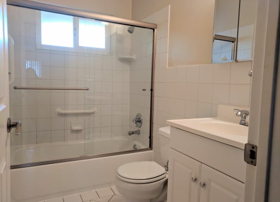 a white bathroom with a shower toilet and sink