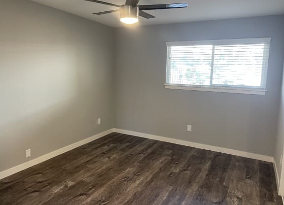 A room with a ceiling fan and a window with blinds.