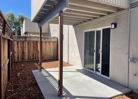 A patio area with a concrete floor and a wooden fence.