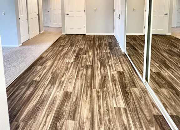 A room with wooden flooring and white walls.