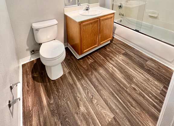A white toilet sits next to a wooden cabinet in a bathroom.