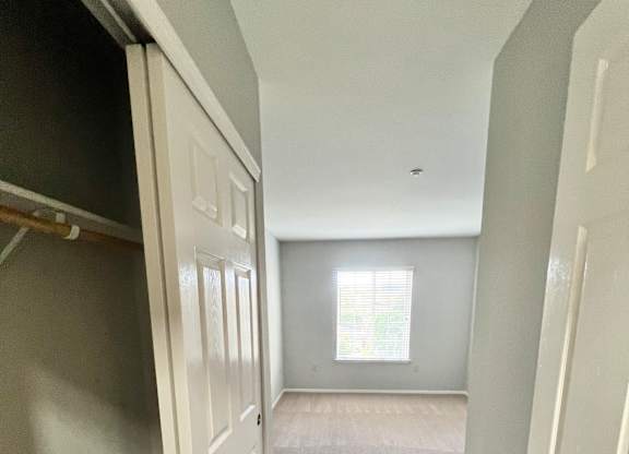 A hallway with white doors and a window.