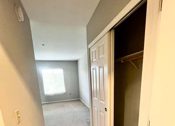 A hallway with a white door and carpeted floor.