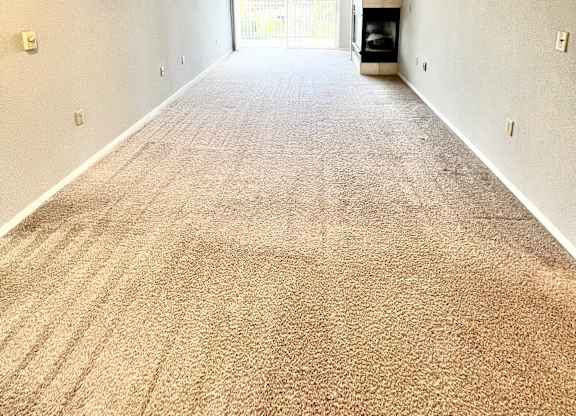 A long hallway with a carpeted floor and a door at the end.