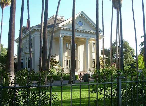 a large white house with columns in front of a fence