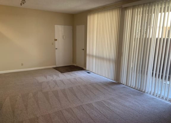 an empty living room with blinds on the window