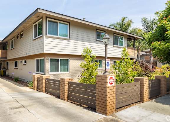 A two-story house with a brown fence and a no parking sign.