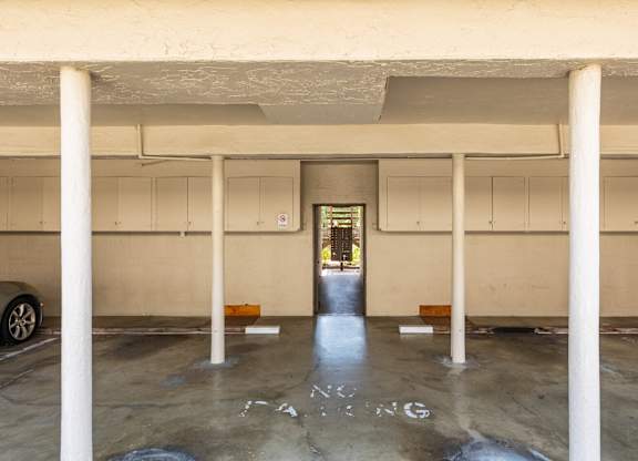 A parking garage with a car parked on the left and a door in the middle.