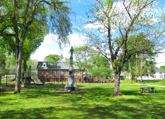 a park with a statue and a building in the background