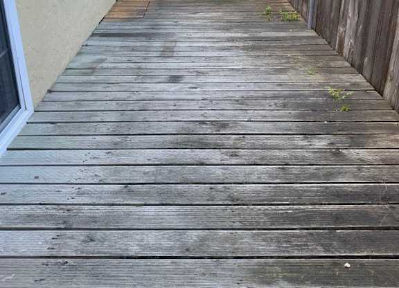 a porch with a wooden deck next to a building