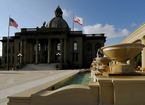 a fountain in front of a building with two flags