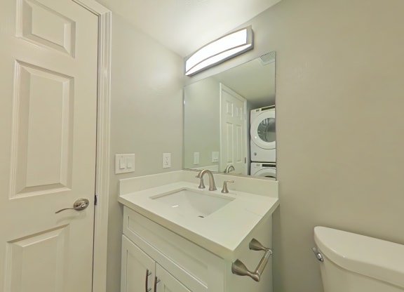 A white bathroom with a sink, mirror, and bathtub.