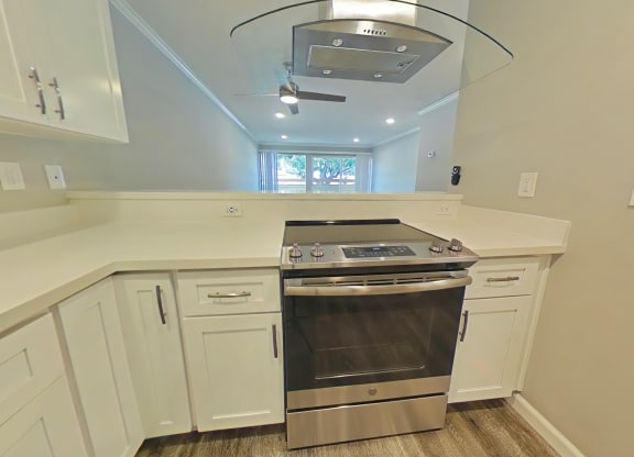 A modern kitchen with a stainless steel oven and white cabinets.