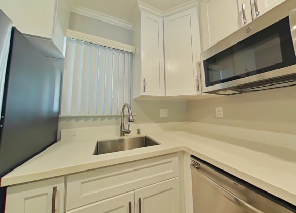 A kitchen with white cabinets and a black refrigerator.
