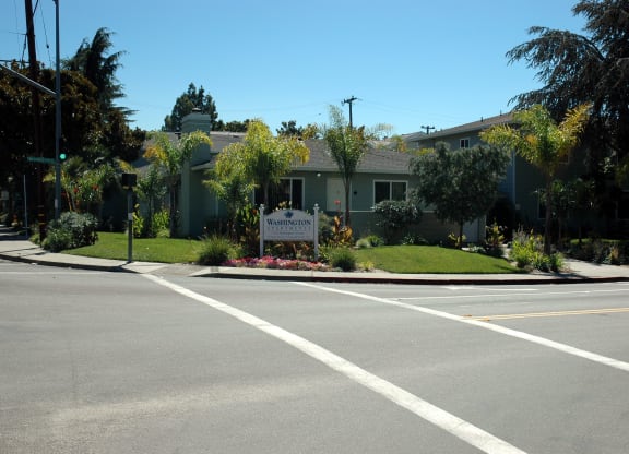 an empty street in front of a building with a sign on the corner