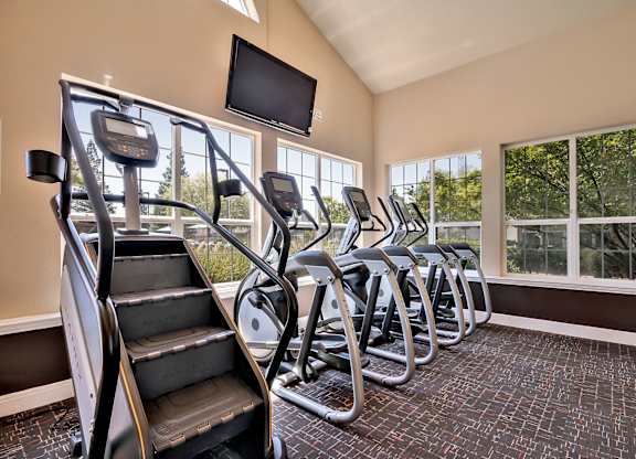 Fitness center with cardio equipment and windows at Rosemeade Apartments, Roseville