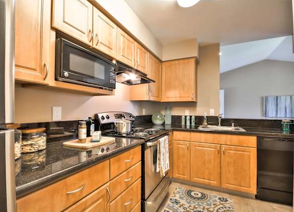 Modern kitchen with black appliances and dark countertops at Rosemeade Apartments, Roseville