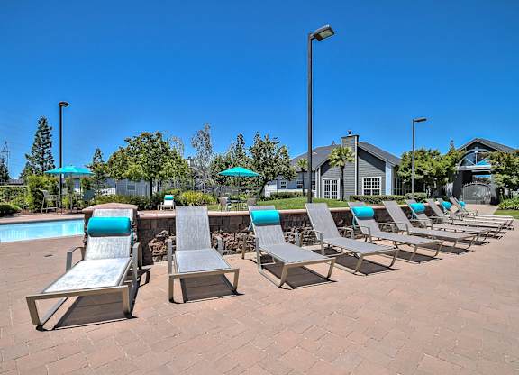 Pool deck with lounge chairs and turquoise accents at Rosemeade Apartments, Roseville, California