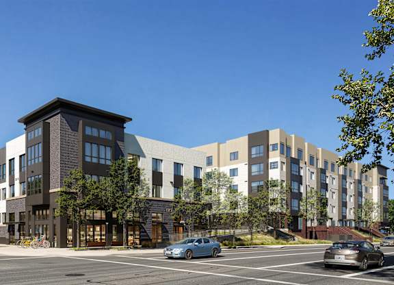 A modern apartment complex with cars parked in front.
