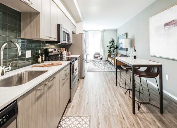 A modern kitchen with a dining area in the background.