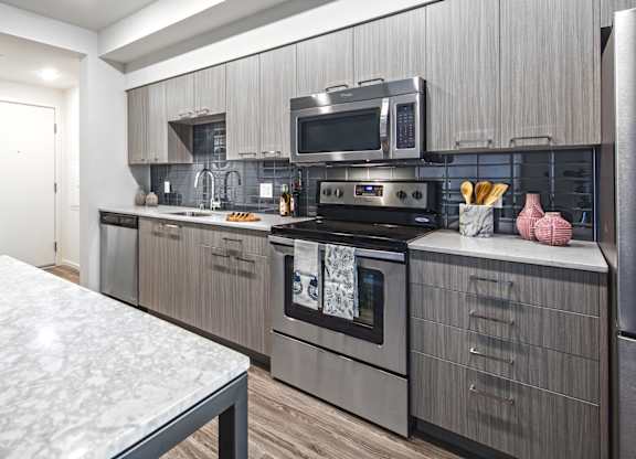 A kitchen with a marble table and modern appliances.