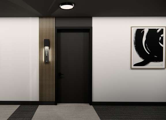 A black door with a gold handle is flanked by two black and white paintings.