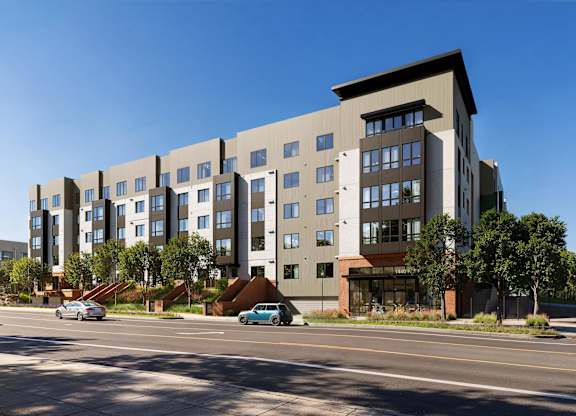 A modern apartment building with cars parked in front.