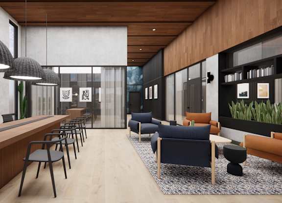 A modern office space with a long wooden desk and chairs, a blue sofa, and a large window with a view of the sky.