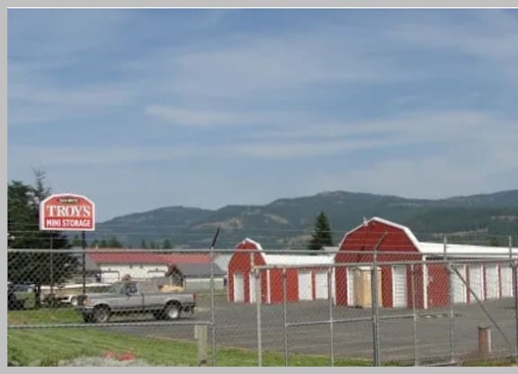 A red barn with a sign that says "Troys" in front of it.