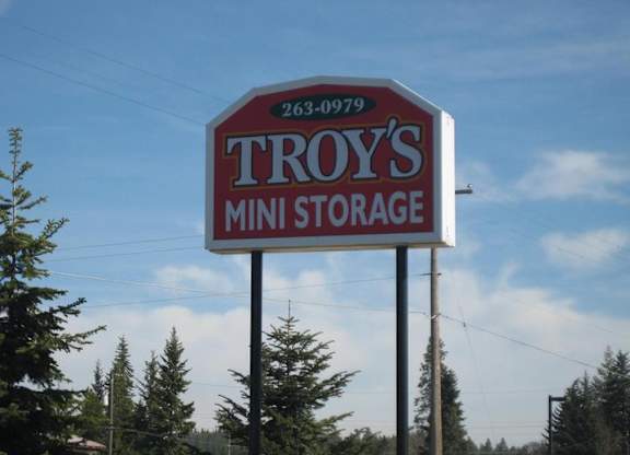 A sign for Troy's Mini Storage with a phone number on it.